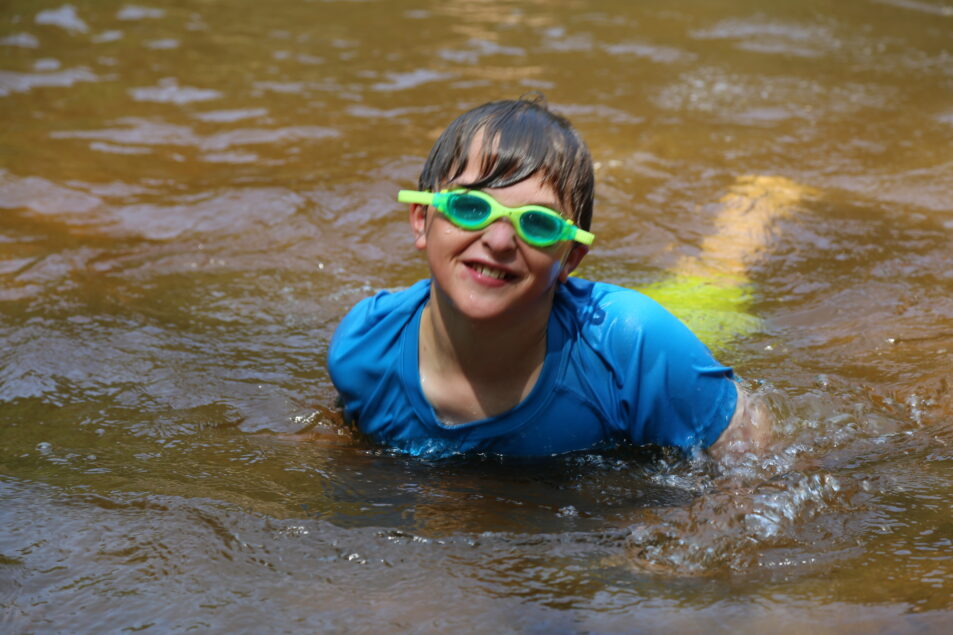 boy with goggles peaks head out of water