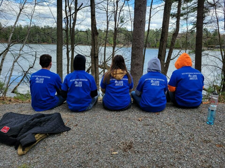 team sits in a line looking at lake