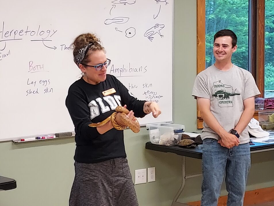 Woman holding snake in front of classroom