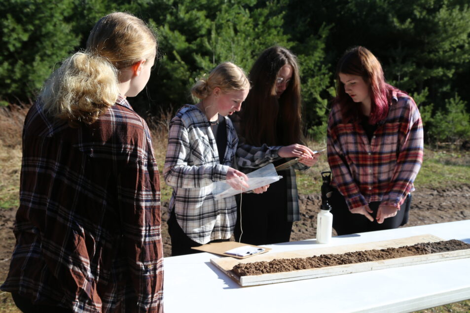 team of girls at table with soil samples looking at tests